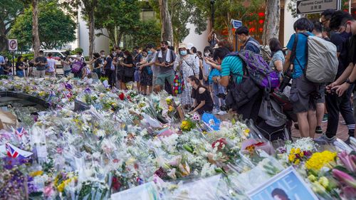 A crying woman kneels down to mourn the death of Queen Elizabeth II outside the British consulate in Hong Kong on September 12.