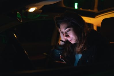 Upset young woman text messaging in her car