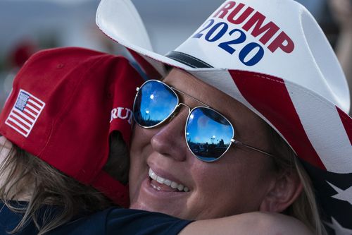 Supporters listen as President Donald Trump speaks at a campaign rally 