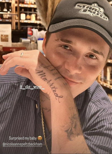 Brooklyn Beckham sitting in a bar showing off his new tattoo that says 'married'.