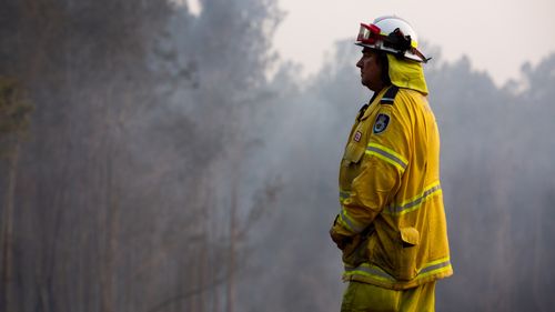 A fireman looks on as a fire burns bushland in Forster, NSW Mid North Coast. Meanwhile snow is falling on the Victorian alps. 