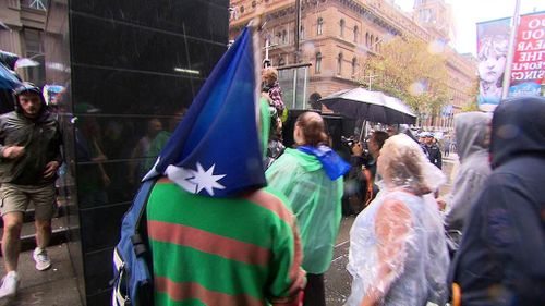 A man drapes an Australian flag over his head at the Sydney rally. (9NEWS)