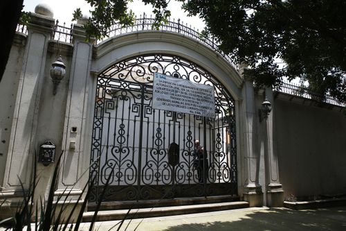 An iron gate shields the mansion from view.