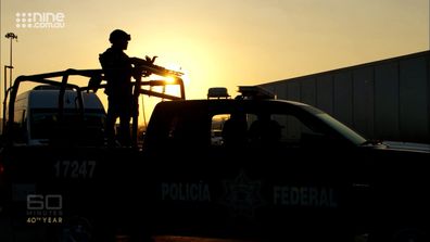 A soldier mans a machine gun as a cavalcade escorting Tom Steinfort and the 60 Minutes team speeds through streets in Mexico.