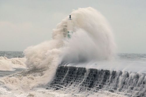 Waves crash over the stone jetty wall in Aberystwyth in west Wales. (AAP)