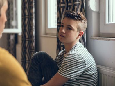 A teenage boy solemnly talking to a male figure