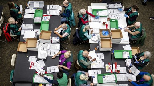 Election workers review ballots at the Denver Elections Department in Denver.