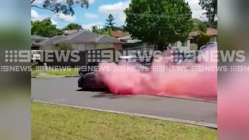 A Mercedes Benz tears up a street in Sydney's west with pink smoke. (9NEWS)