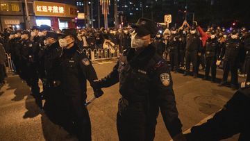 Chinese policemen form a line to stop protesters marching in Beijing.