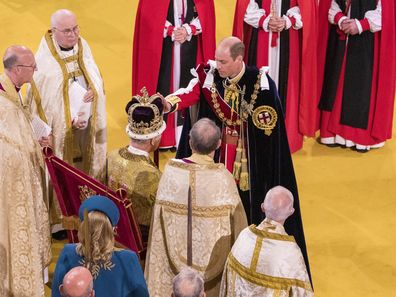 Britain's Prince William, right, touches the crown and pledges loyalty to King Charles III, during his coronation ceremony, in Westminster Abbey, in London, Saturday May 6, 2023. 