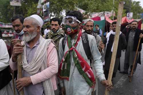Des partisans de l'ancien Premier ministre Imran Khan se rassemblent avec des bâtons devant la résidence de Khan, à Lahore, au Pakistan, le vendredi 17 mars 2023. 