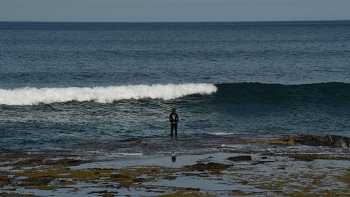 A boy stands on a reef at the waters edge near the ocean baths at Newcastle during the statewide COVID-19 lockdown. Newcastle, NSW. 10th September, 2021. Photo: Kate Geraghty