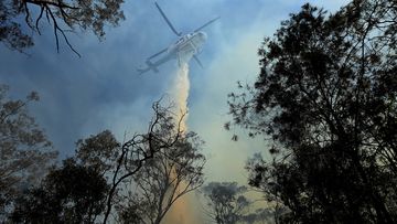 A helicopter dumps water on a bushfire on Silverdale Road in Wallacia