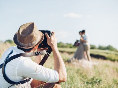 Wedding photographer takes pictures of bride and groom in nature in summer, fine art photo
