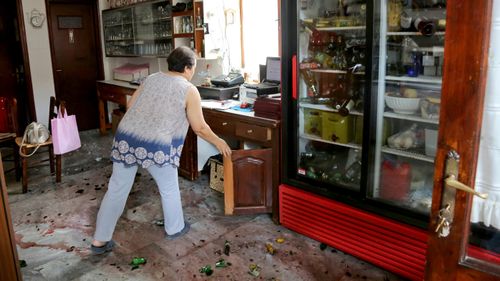 A woman clears her shop after an earthquake in the village of Plomari on the northeastern Greek island of Lesbos. (AAP)