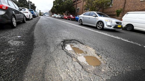 A car swerves to miss a pothole in the Sydney suburb of Queens Park.