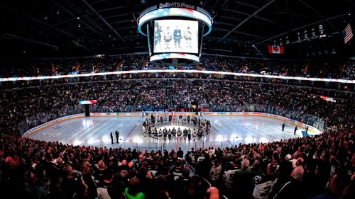 The Winnipeg Jets and the Chicago Blackhawks come together at the centre ice wearing Broncos on the back of their jerseys for a moment of silence for the Humboldt Broncos bus crash victims before NHL hockey game action in Winnipeg, (AP).