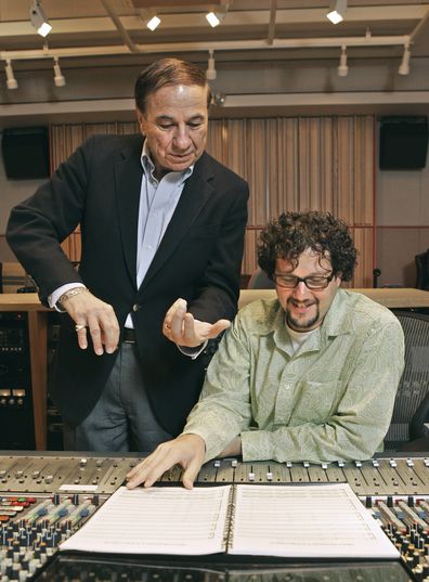 FILE - Composers Richard M. Sherman, left, who, along with his brother Robert, wrote the song "It's a Small World" for the Disneyland ride of the same name, and Michael Giacchino, right, who composed the driving music for Disneyland's newly-redesigned "Space Mountain" ride, work in a sound room at Walt Disney Imagineering offices in Glendale, Calif.,  July 5, 2005. Sherman, one half of the prolific, award-winning pair of brothers who helped form millions of childhoods by penning classic Disney t
