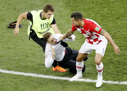 Dejan Lovren (R) of Croatia tries to take an intruder (C) out of the field during the second half of the World Cup final against France at Luzhniki Stadium in Moscow on July 15, 2018. Russian protest group and musical act Pussy Riot has claimed responsibility for the incident. (Kyodo via AP Images) 