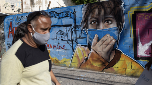 A man walks past a mural referencing the COVID-19 pandemic, painted in honour of health workers in Rio de Janeiro, Brazil, Thursday, May 21, 2020. The mural is by graffiti artist Angelo Campos, 39, who has lost two relatives to the new coronavirus. (AP Photo/Silvia Izquierdo)