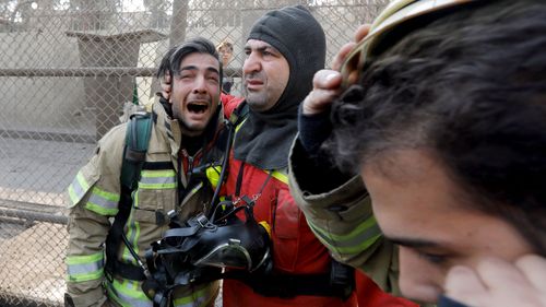 A firefighter consoles his comrade after the collapse of Iran's oldest high-rise, the 15-storey Plasco building in downtown Tehran. (AFP)