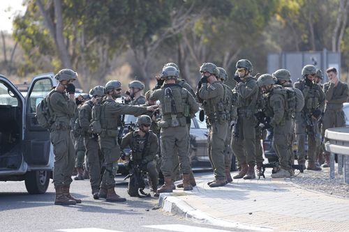 Israeli soldiers gather on the road in central Israel Israel on Saturday, Oct. 7, 2023. Palestinian militants in the Gaza Strip infiltrated Saturday into southern Israel and fired thousands of rockets into the country while Israel began striking targets in Gaza in response