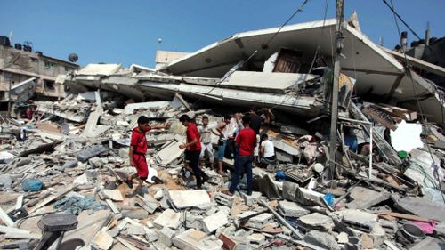 Palestinians inspect rubble in Gaza for anything useful. (Getty)