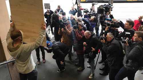 Reporters surround a demonstrator outside court. (Image: Sean Davidson)