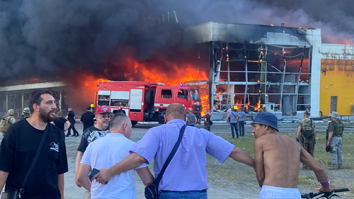 People watch as smoke bellows after a Russian missile strike hit a crowded shopping mall, in Kremenchuk, Ukraine, Monday, June 27, 2022. 