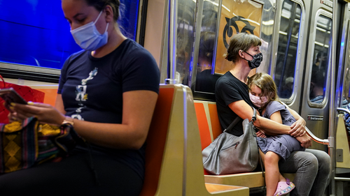 FILE - In this Aug. 17, 2020, file photo, a child rests on a subway car while riders wear protective masks due to COVID-19 concerns in New York. (AP Photo/John Minchillo, File)