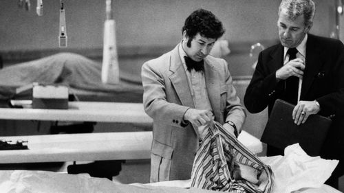 San Francisco homicide inspectors David Toschi, left, and William Armstrong go through a murder victim's clothes