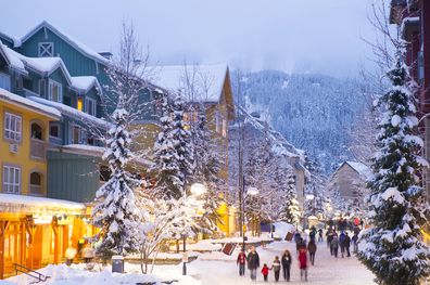 Whistler's world class pedestrian village filled with shops, hotels and restaurants blanketed with fresh snow at dusk