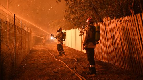 Firefighters fight flames close to homes in Corryton Court, Wattle Grove in Sydney. (AAP)