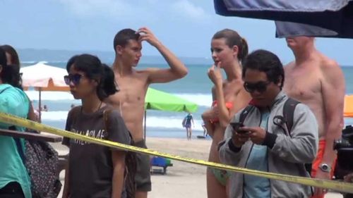 Tourists watch on at Kuta beach. (9NEWS)