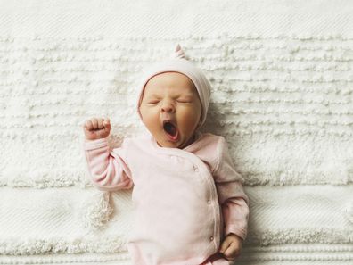 A close-up of an adorable baby girl, 4.5 weeks old, yawning. 