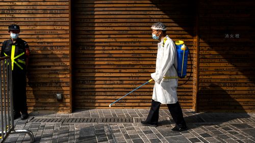 A workers sprays disinfectant to prevent COVID-19 at a shopping area in Beijing.