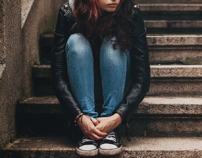 Lonely teenager sitting on stairs with copy space