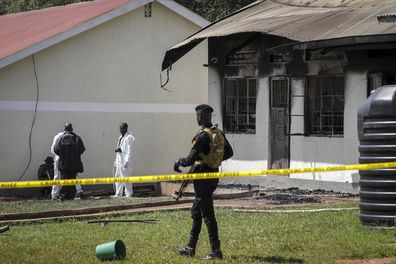 Security forces and forensics officers stand in front of a burned dormitory at the scene of a fire at the Salama School for the Blind in Luga village, Mukono district, Uganda Tuesday, Oct. 25, 2022.
