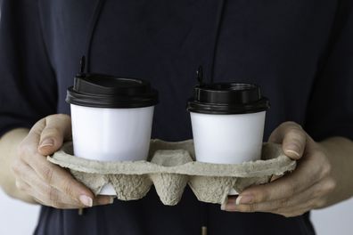 Unrecognizable caucasian woman is  holding two disposable cups.
