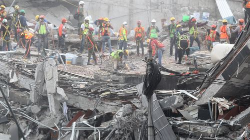 Rescue tream members search for victims in the rubble of a collapsed building. (AAP)