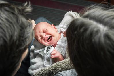 Newborn baby colic close up. Young parents and crying baby 1 month old.