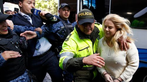 A police officer escorts Australian Cassandra Sainsbury to a court hearing in Bogota, Colombia. (AAP)