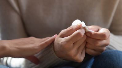 Woman holding tissues, grieving. Sad woman holding tissues.