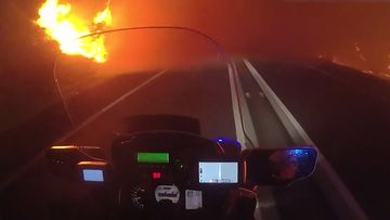 A Queensland Police motorbike travels through the fire.