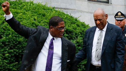 Bill Cosby (right) walks out the courthouse as his spokesman Andrew Wyatt celebrates the mistrial. (AFP)