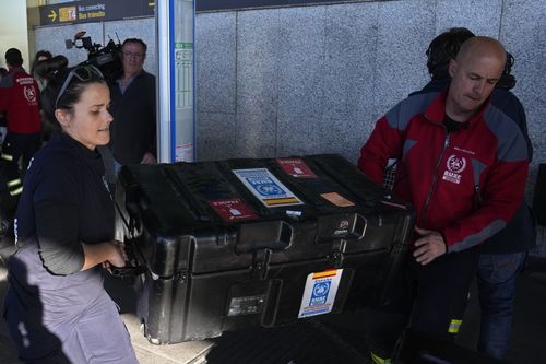 Spanish firefighters load a case onto an airport trolley at Barajas international airport on the way to help with a rescue mission in Turkey before boarding a flight in Madrid, Spain, Monday, Feb. 6, 2023.  