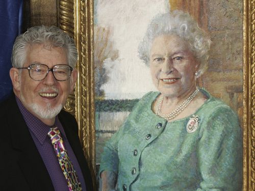 Artist Rolf Harris stands with his portrait of Britain's Queen Elizabeth II, at its unveiling at Buckingham Palace, London, Monday Dec. 19, 2005. 