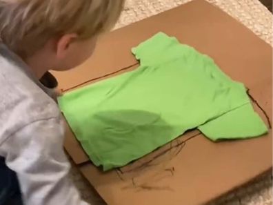 Little kid folding clothes with homemade clothes folder