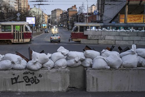 A driver passes through a barricade built by territorial defence units downtown in Kyiv, Ukraine, Saturday, March 19, 2022. 