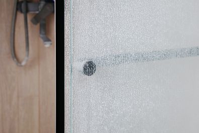 Limescale on transparent glass of shower cabin close-up, plumbing maintenance concept